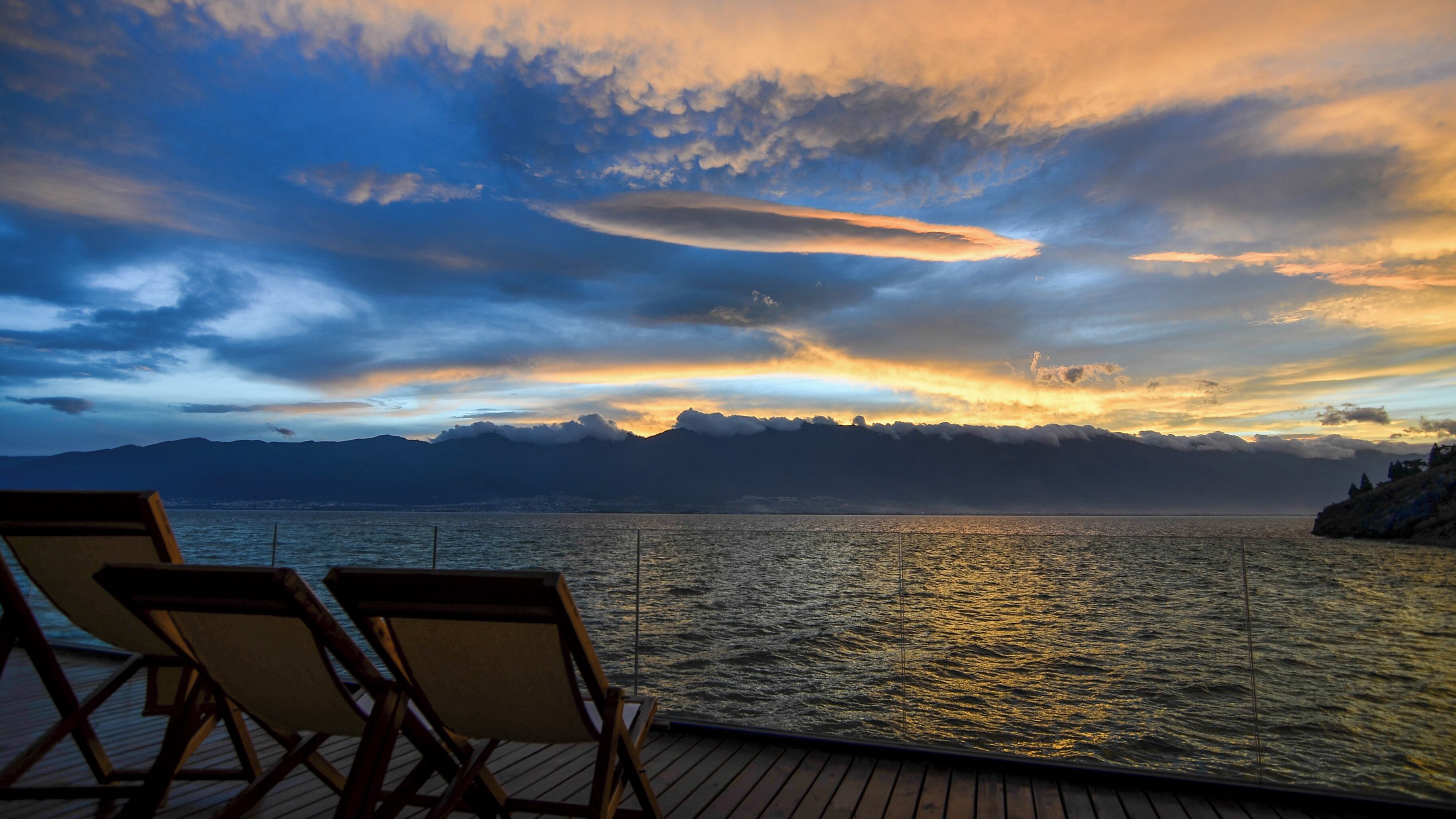 Una terrazza con due poltrone vista acqua e montagne sullo sfondo.