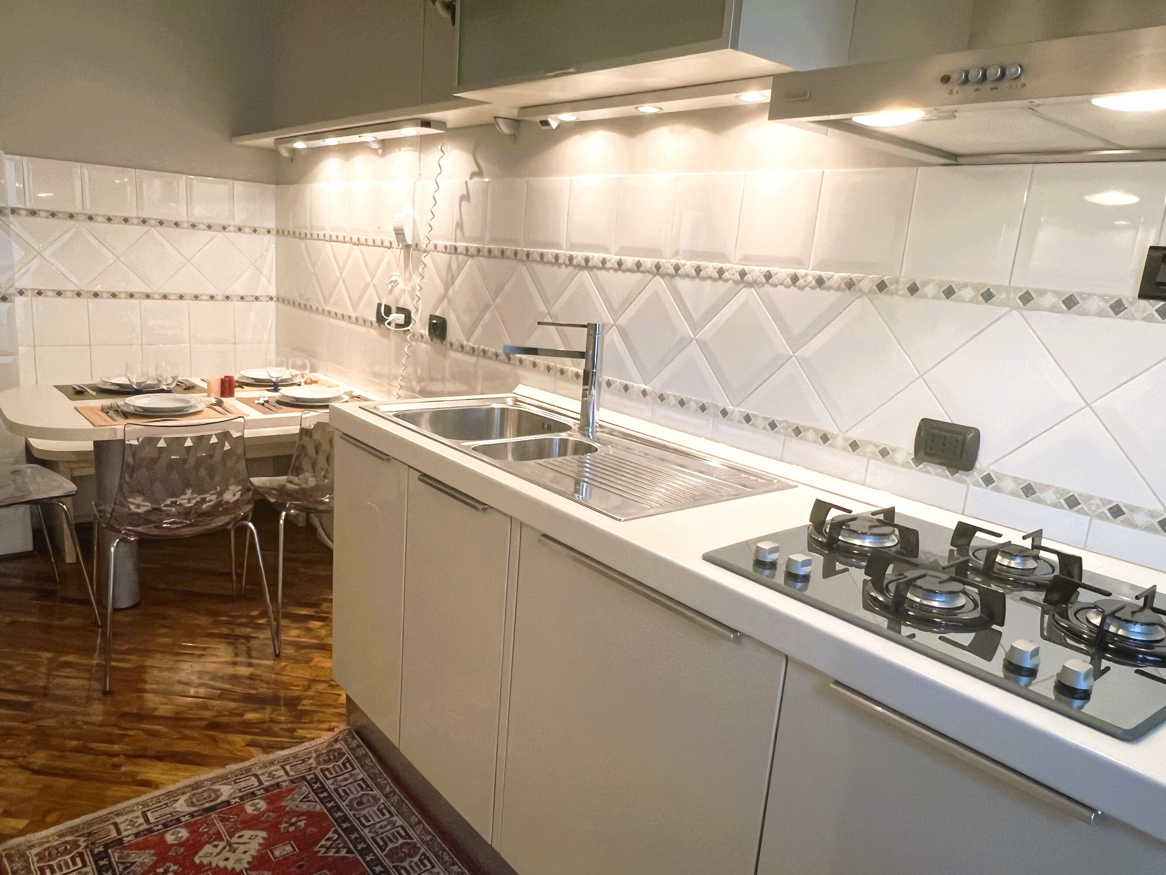 A modern kitchen with white cabinets, a gas stove, and a tiled backsplash.