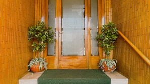 A wooden door with glass panels, flanked by two potted plants. - Verrazzano House Florence (Firenze)