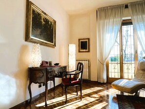 A room with a wooden desk, a chair, a radiator, and a window with curtains. - Verrazzano House Florence (Firenze)