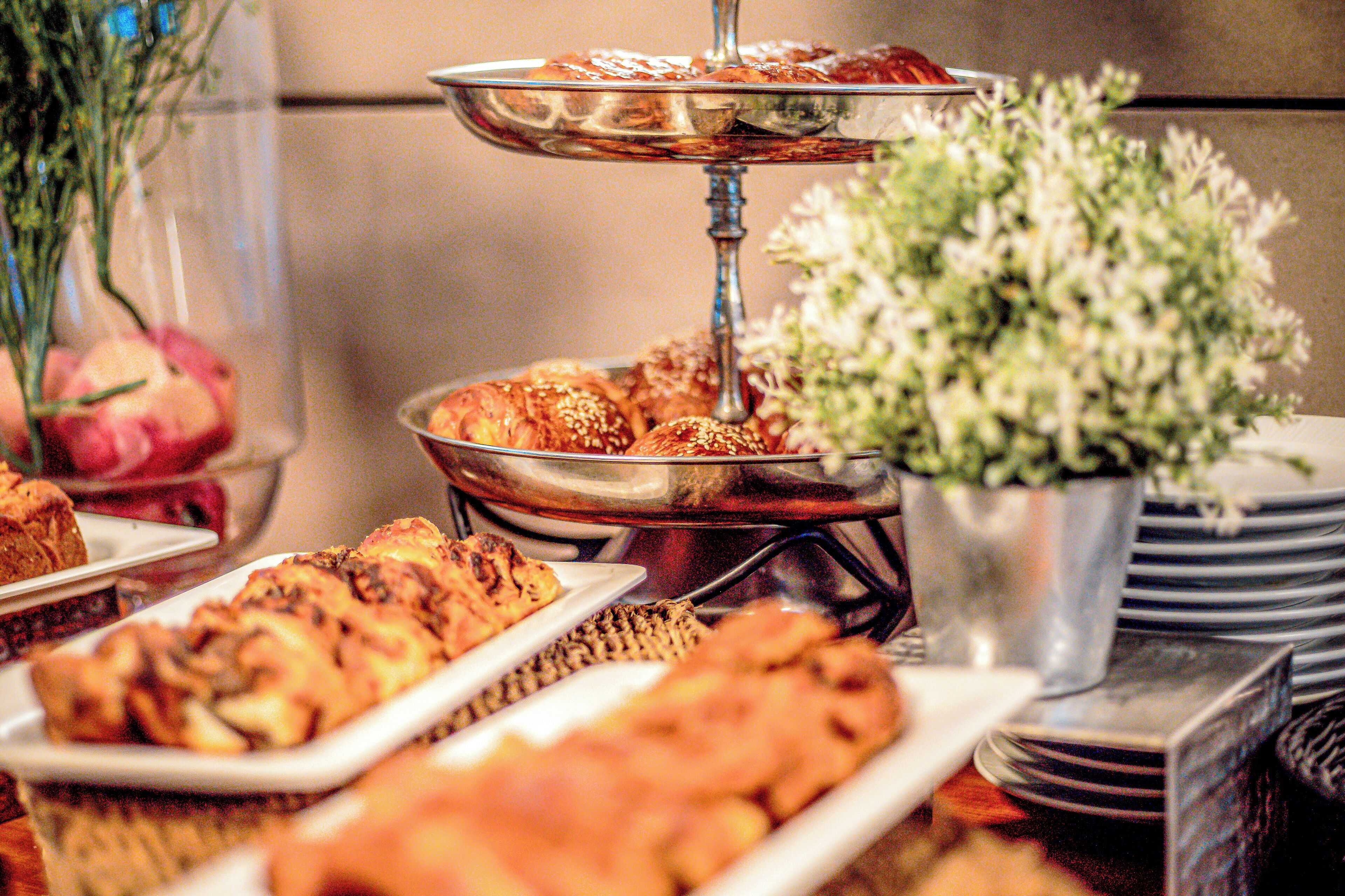 A buffet table with various baked goods and a decorative vase.