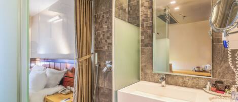 A hotel bathroom with a shower, a sink, and a mirror.