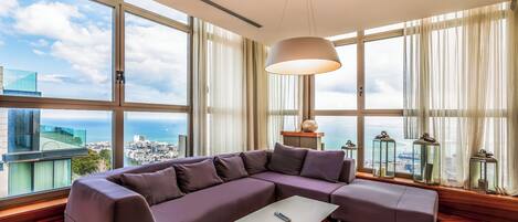 A modern living room with a sectional sofa, a coffee table, and large windows offering a city view.