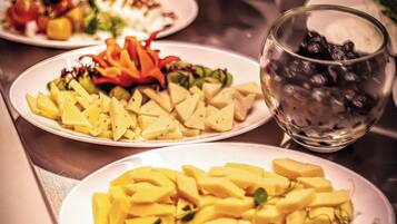 Un tavolo da buffet con diversi piatti, tra cui insalate, frutta e un bicchiere di bevanda fredda.