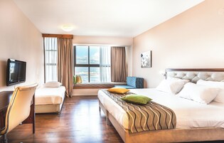 A hotel room with a bed, a desk, a chair, a television, and a window with curtains.