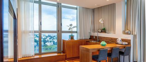 Cozinha moderna com armários de madeira, um espaço bar e amplas janelas com vista para a cidade.