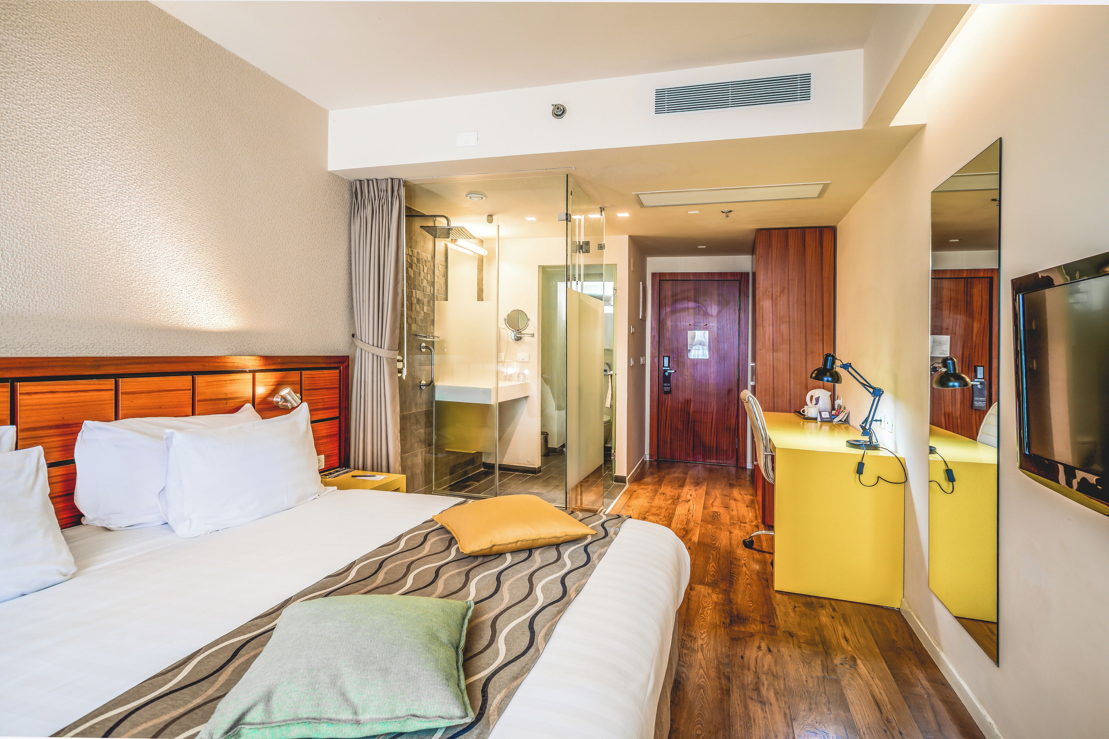 Une chambre d’hôtel avec un lit, une table de chevet et un miroir.