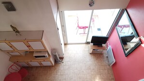 A room with a TV, a sofa, a small table, and a red wall. - Spacious apartment for 6, Valras-Plage center, 10m from the beach (Valras-Plage)