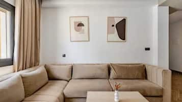 A modern living room with a beige sectional sofa, a coffee table, and two framed abstract artworks on the wall.
