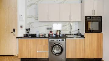A compact kitchen with wooden cabinets, a built-in washing machine, and a microwave.