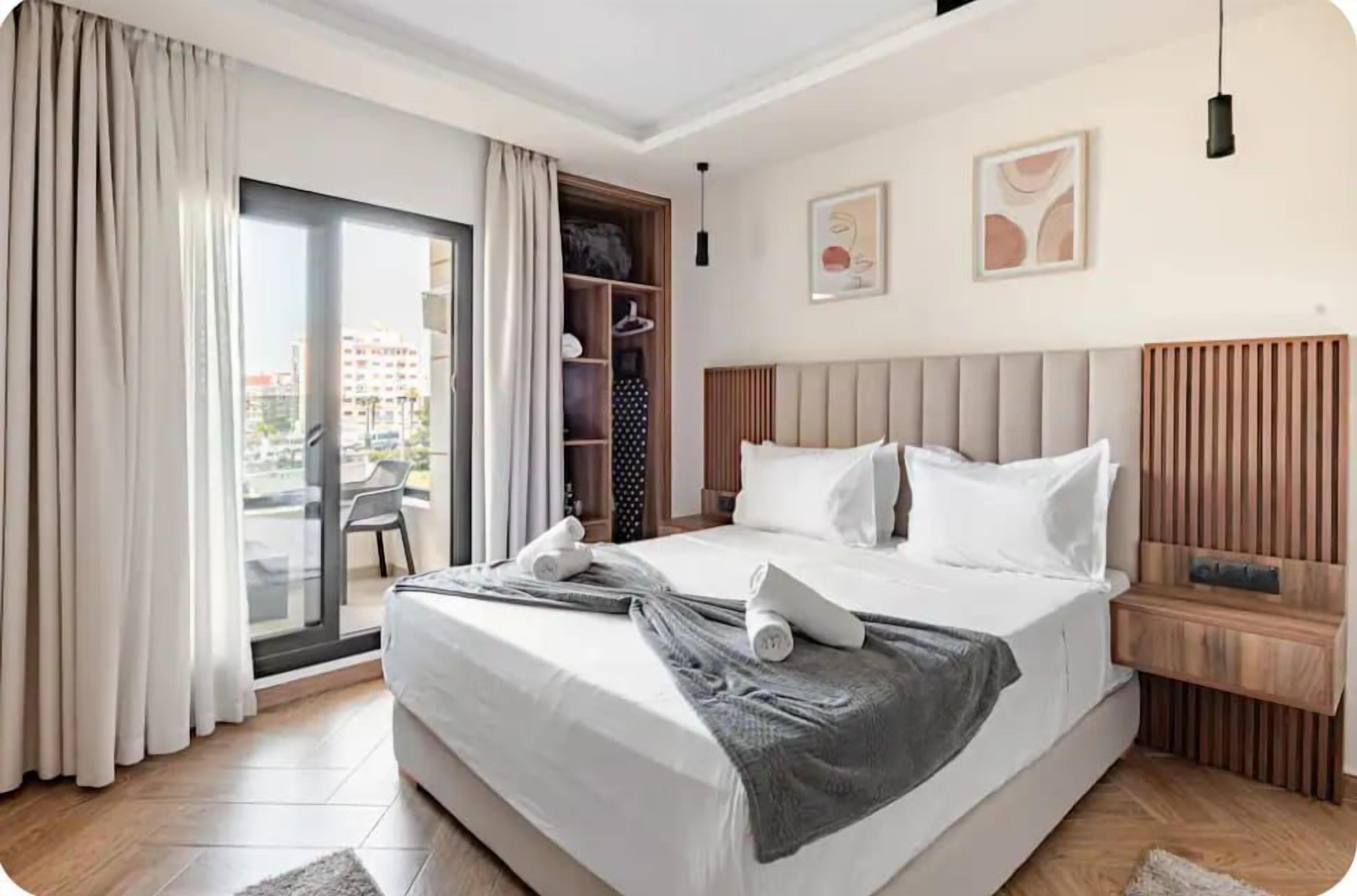 Hotelkamer met een groot bed, een kledingkast, een zithoek met een stoel en uitzicht door een glazen deur.