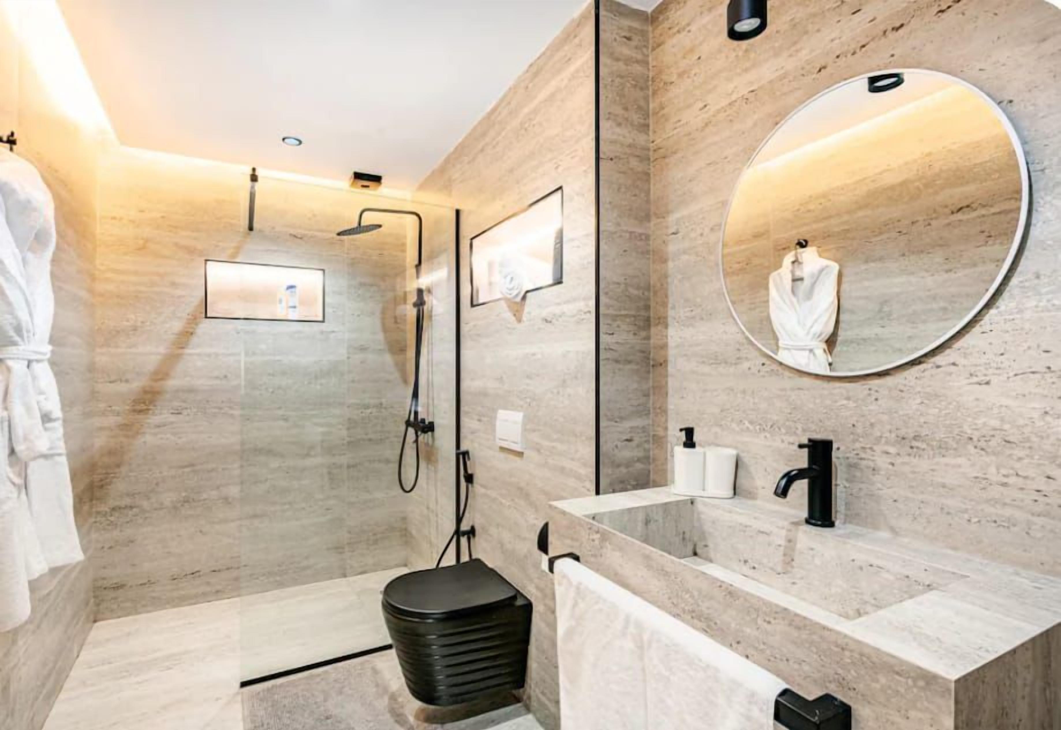 Casa de banho moderna com chuveiro amplo, um espelho grande e toucador com lavatório.
