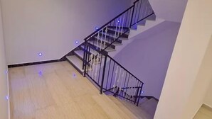 A spacious room with a wooden floor, a staircase with black railings, and recessed ceiling lighting. - CENTRICO (Tangier)