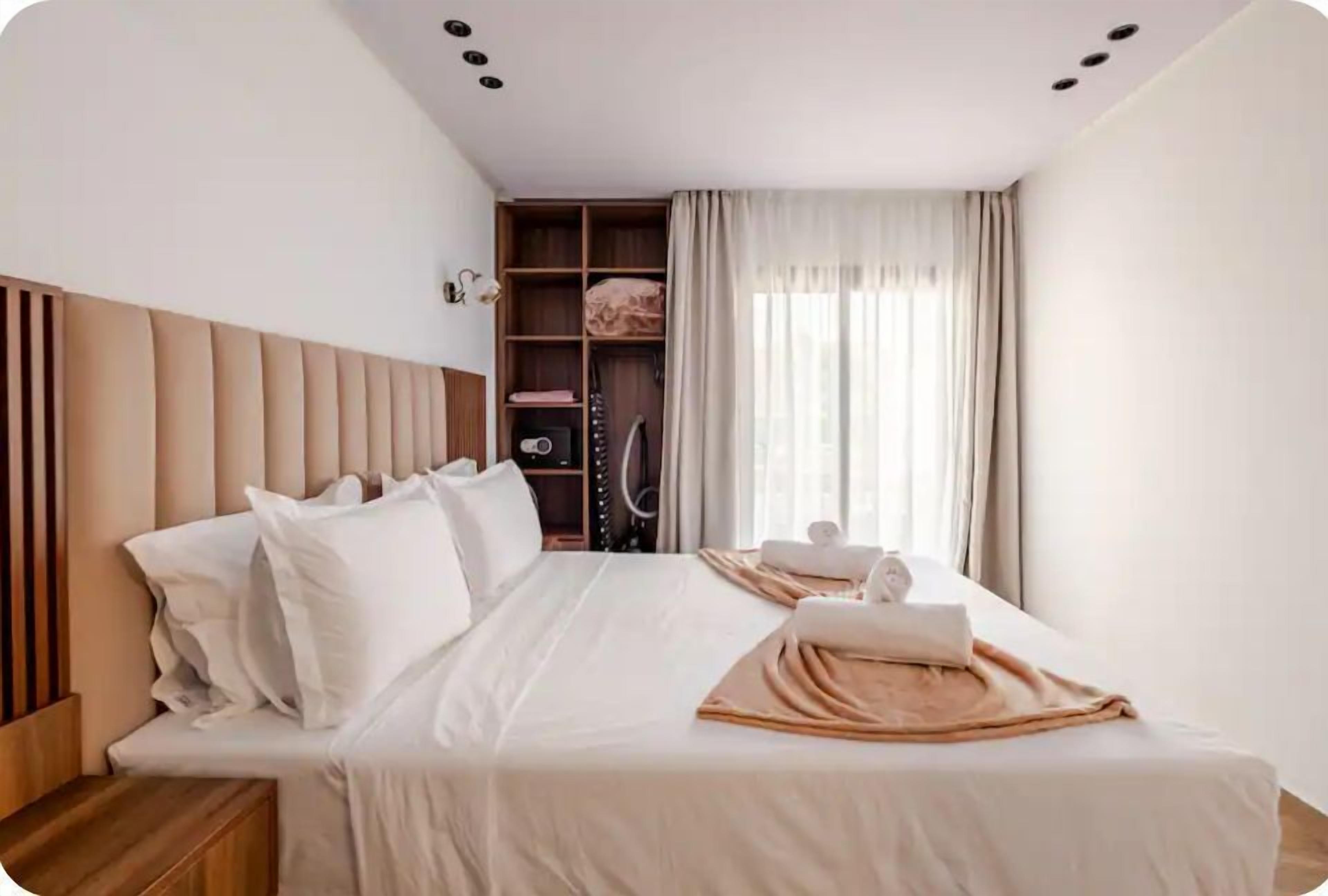 A hotel room with a bed, a wardrobe, and a window with curtains.