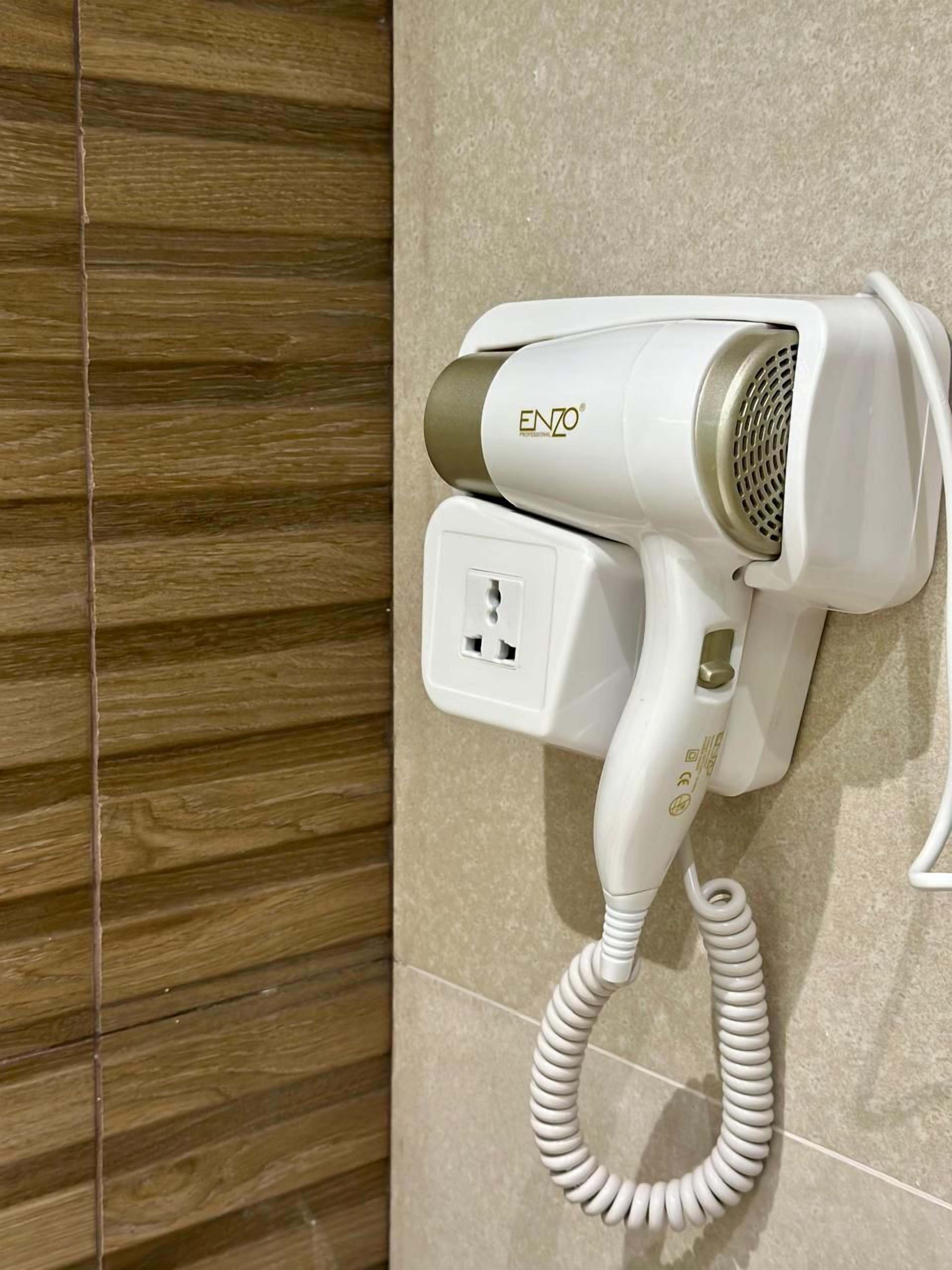 Un secador de pelo montado en la pared con un cable enrollado.