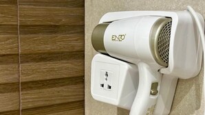 A hair dryer mounted on a wall with a coiled cord. - CENTRICO (Tangier)