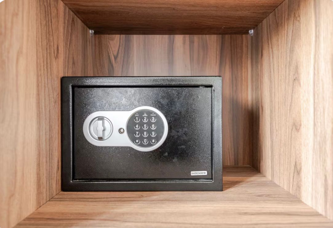 A safe deposit box with a combination lock, housed in a wooden cabinet.