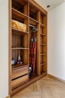 Un armario de madera con estantes y espacio para colgar, una plancha pequeña y una aspiradora.