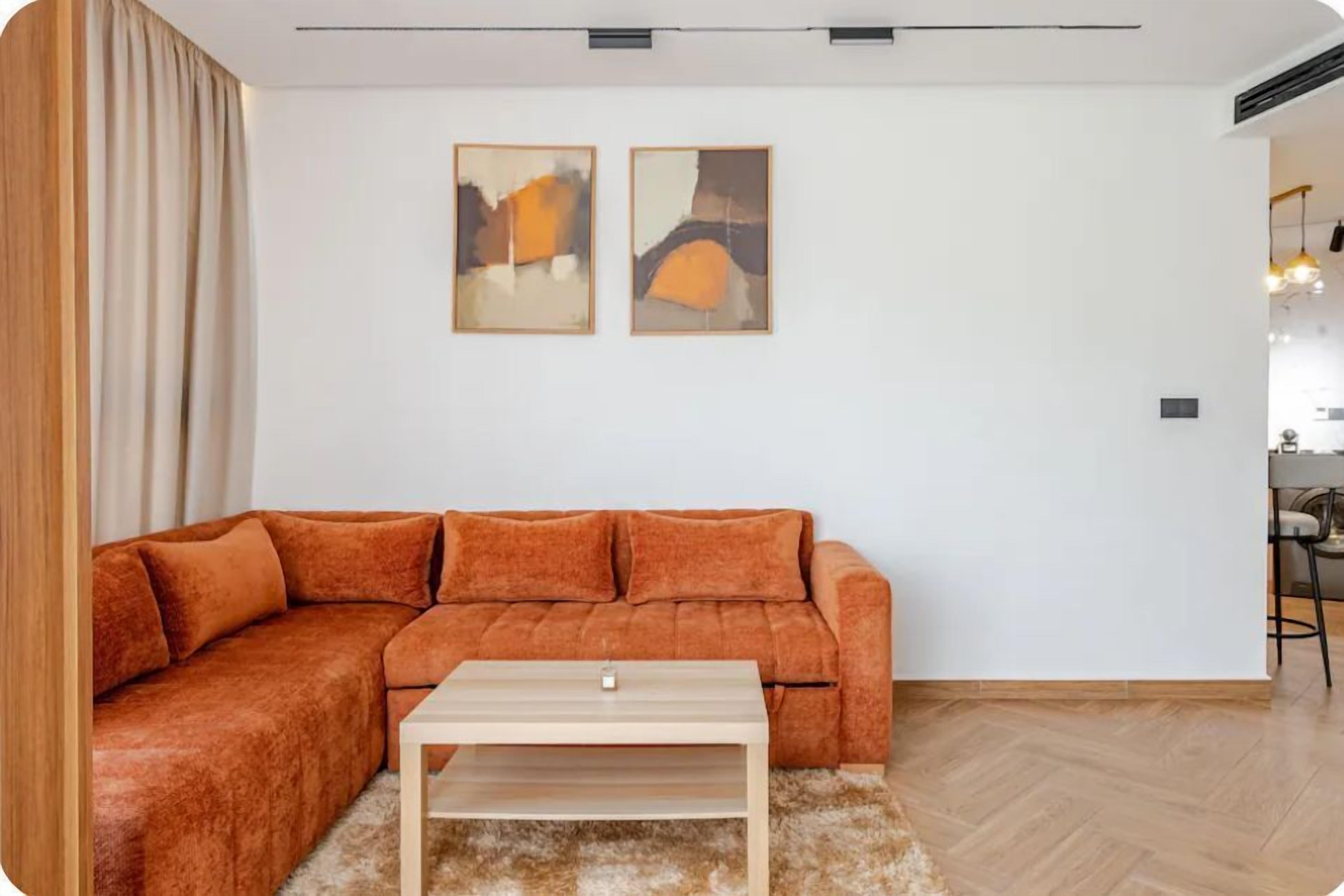 A living room with a sectional sofa, a coffee table, and two abstract paintings on the wall.