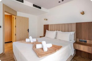 Habitació d'hotel amb un llit gran, un armari de fusta, una taula de nit i una làmpada penjada a la paret.