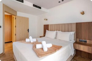 Habitación de hotel con una cama grande, un armario de madera, una mesita de noche y un aplique de pared.
