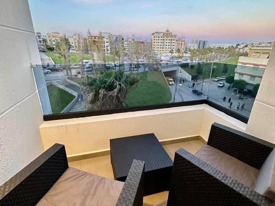 Un balcon donnant sur un paysage urbain, avec des bâtiments et une route.