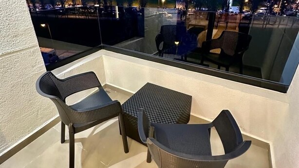 A balcony with two chairs and a small table, overlooking a cityscape at dusk. - CENTRICO (Tangier)