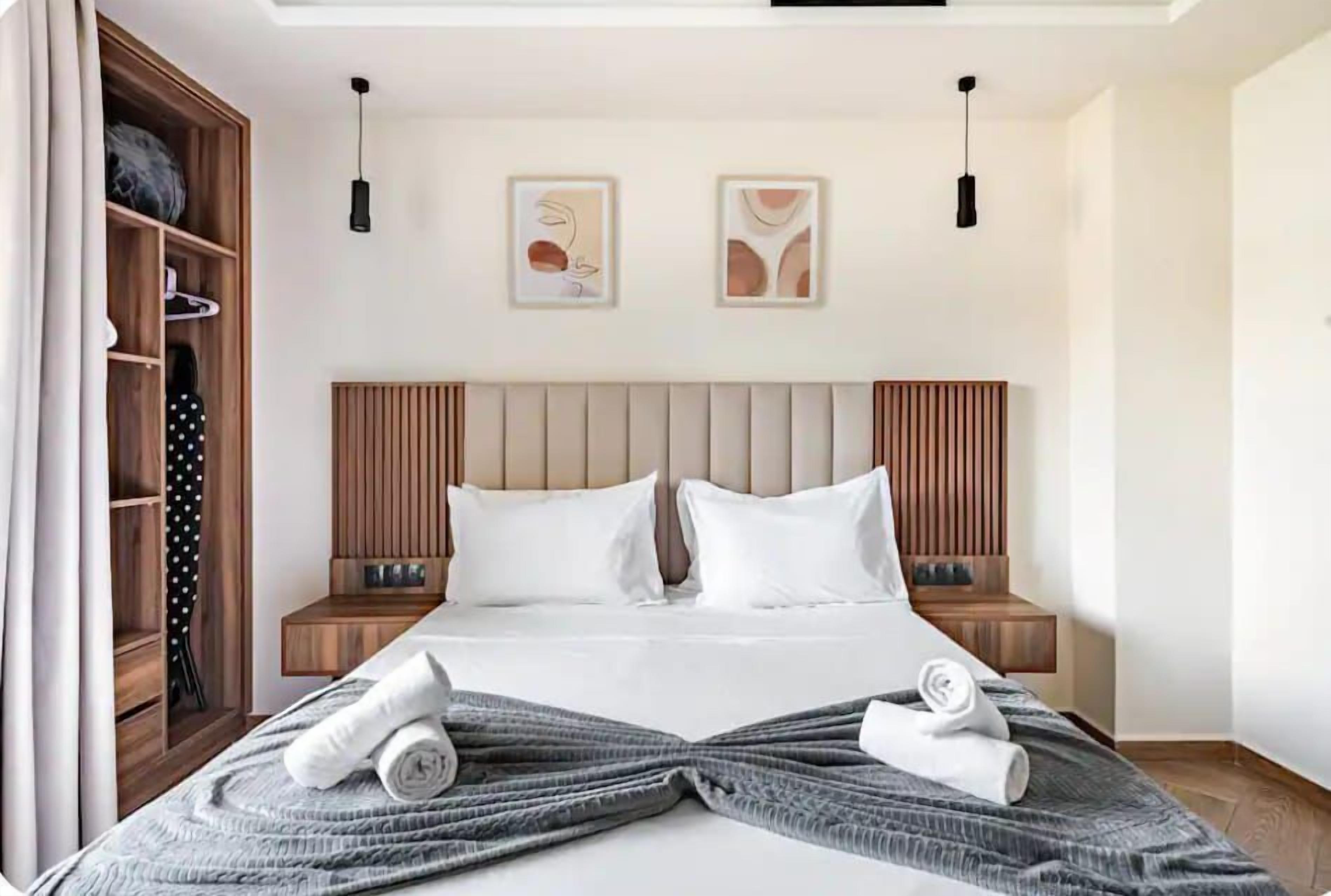 Une chambre d’hôtel avec un lit, deux tables de chevet, une armoire et des œuvres d’art accrochées au mur.