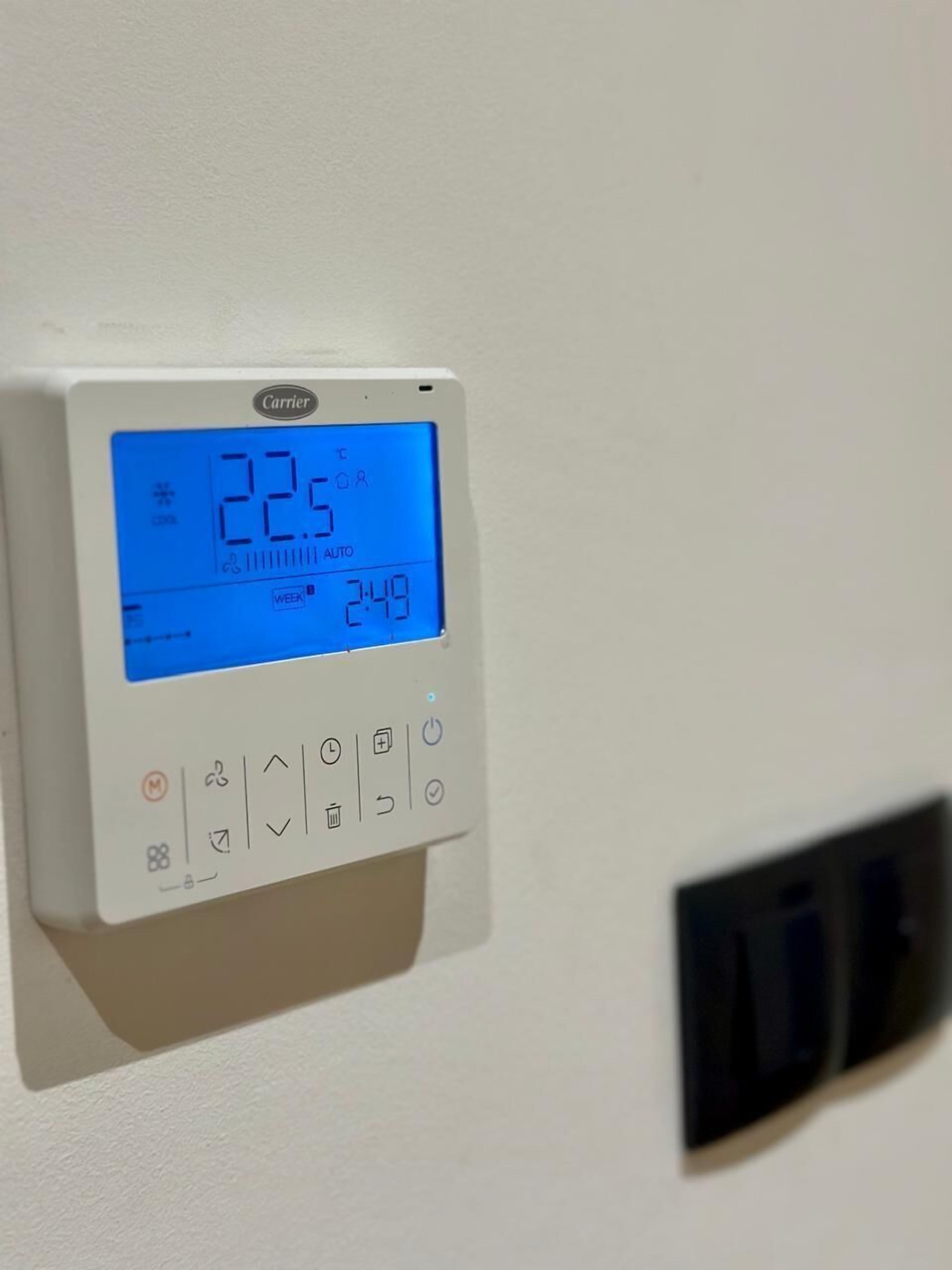 Een Carrier-thermostaat met een digitaal scherm dat 22,5°C aangeeft en een tijd van 2:49 toont.