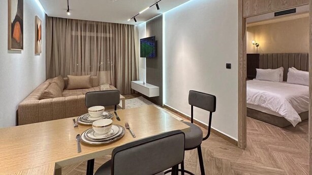 Une chambre d’hôtel moderne comprenant un coin repas, un canapé, un lit et un téléviseur.