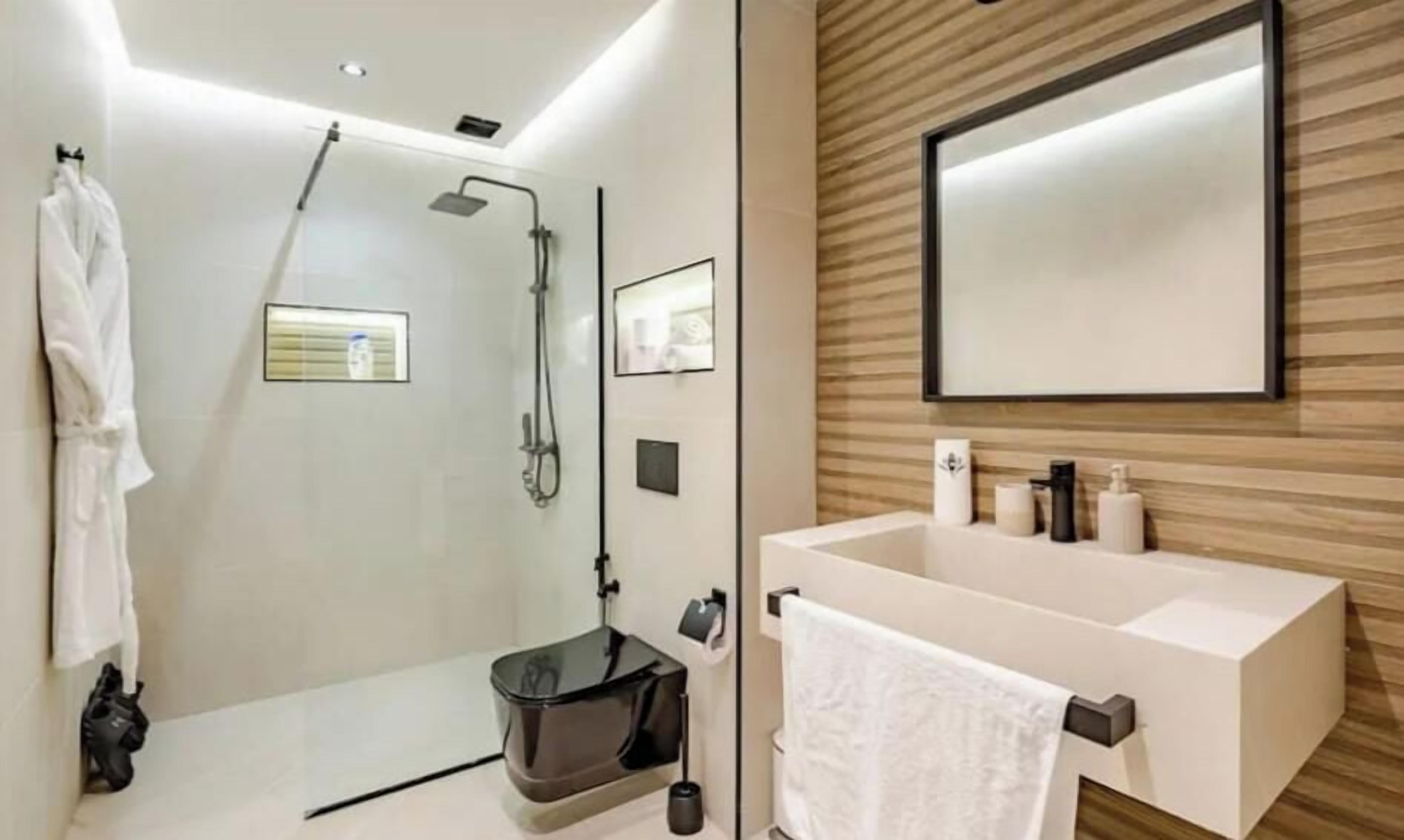 A modern bathroom with a glass-enclosed shower, a large mirror, and a white sink with a towel rack.