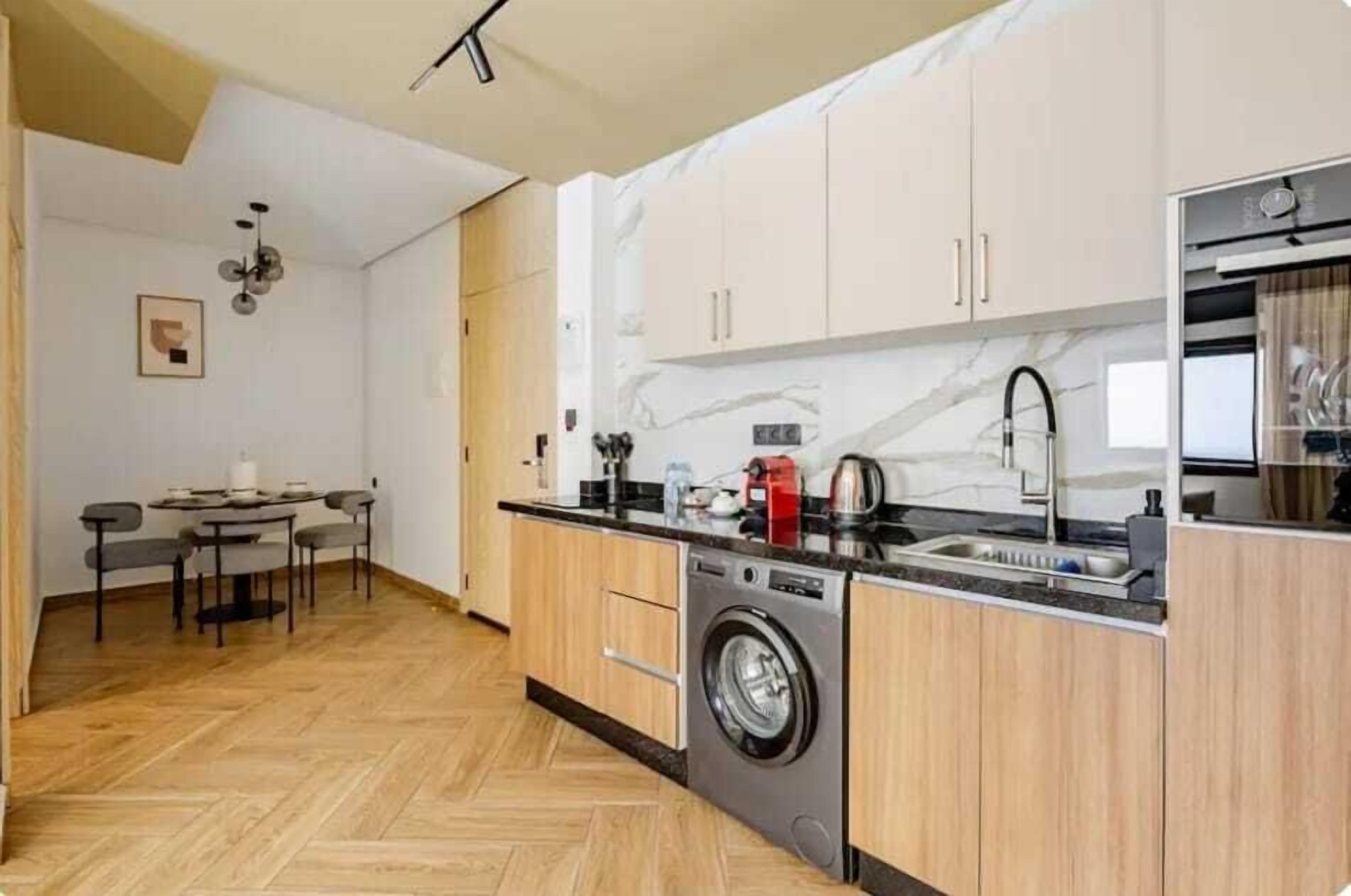 Una cucina moderna con lavatrice integrata, mobili in legno e pavimento a spina di pesce.