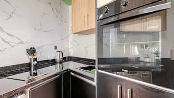 Una cocina con salpicadero de mármol, electrodomésticos de acero inoxidable y armarios de madera.