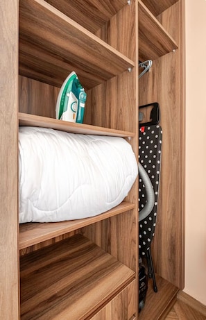 A wooden storage unit with a white mattress, an iron, and a polka-dotted bag.