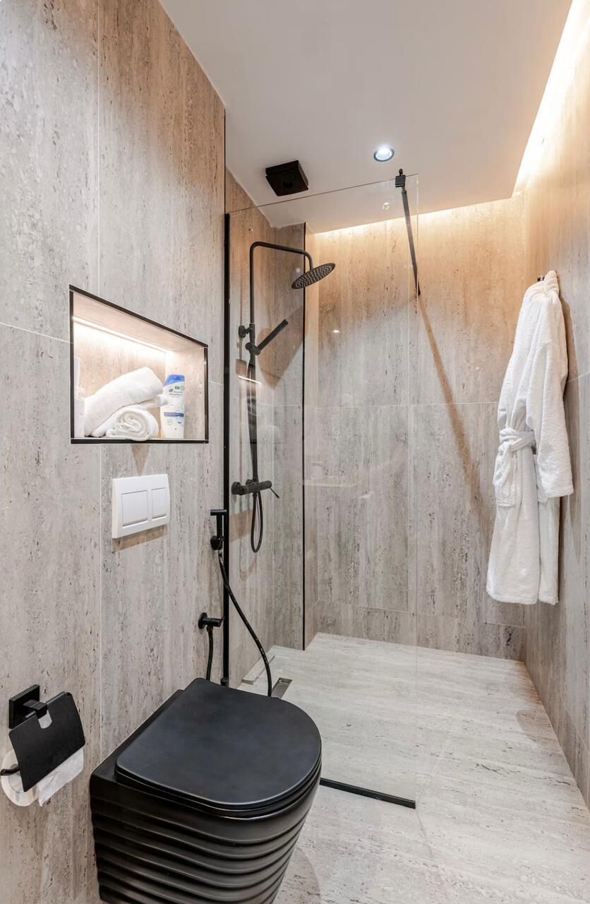 Une salle de bain moderne avec une douche à parois de verre, un porte-serviettes blanc et des toilettes noires.
