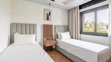 A hotel room with two beds, a wooden nightstand, a framed picture, and a window with curtains.