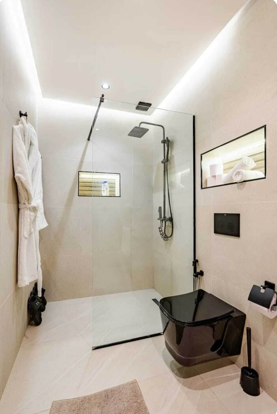 A modern bathroom with a glass shower enclosure, a towel rack, a toilet, and a bidet.