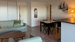 A modern living room with a sofa, a coffee table, and a dining area with a table and chairs.