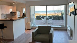 A modern kitchen with a large sliding glass door leading to an outdoor patio with a view of the beach.