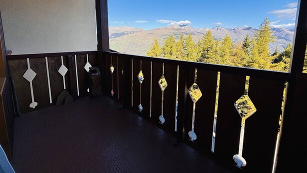 Un balcon avec vue sur les montagnes et les arbres.
