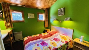 Une pièce comprenant un lit, un bureau, une chaise, un radiateur et une fenêtre.