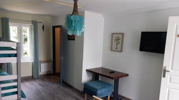 A room with a bunk bed, a desk with a chair, a television, and a door.