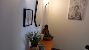 A room with a wooden bench, a Buddha statue, a framed artwork, a mirror, and a potted plant. - 3 BEDROOMS Villedieu les poeles MONT SAINT MICHEL (Sainte-Cécile)