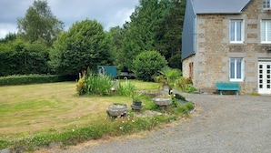 A stone house with a gravel driveway and a well-maintained lawn. - 3 BEDROOMS Villedieu les poeles MONT SAINT MICHEL (Sainte-Cécile)