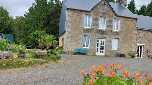 A stone house with a gravel driveway, a bench, and a garden with flowers. - 3 BEDROOMS Villedieu les poeles MONT SAINT MICHEL (Sainte-Cécile)