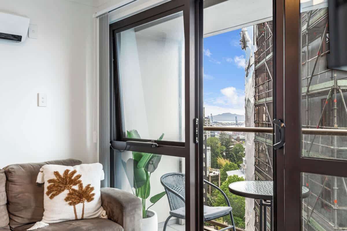 Un balcón con vistas a un paisaje urbano, una planta en maceta y una silla.