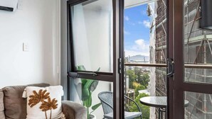 A balcony with a view of a cityscape, a potted plant, and a chair. - Central 3BR Full Kitchen & Amenities Zodiak Stays (Auckland)