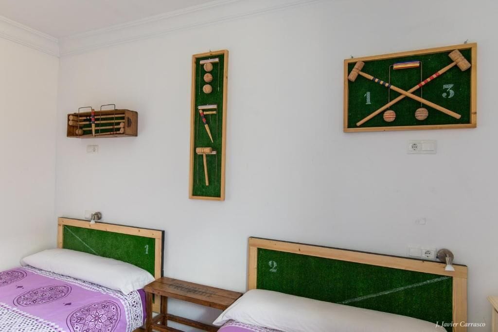 A room with two beds, a wooden table, and two green chalkboards with numbers and objects.
