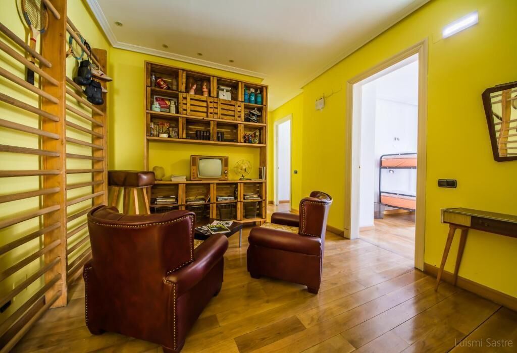 Una sala de estar con una estantería de madera, sillones de cuero y un televisor.