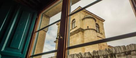 A window with a view of a historic building with arched windows and a dome.